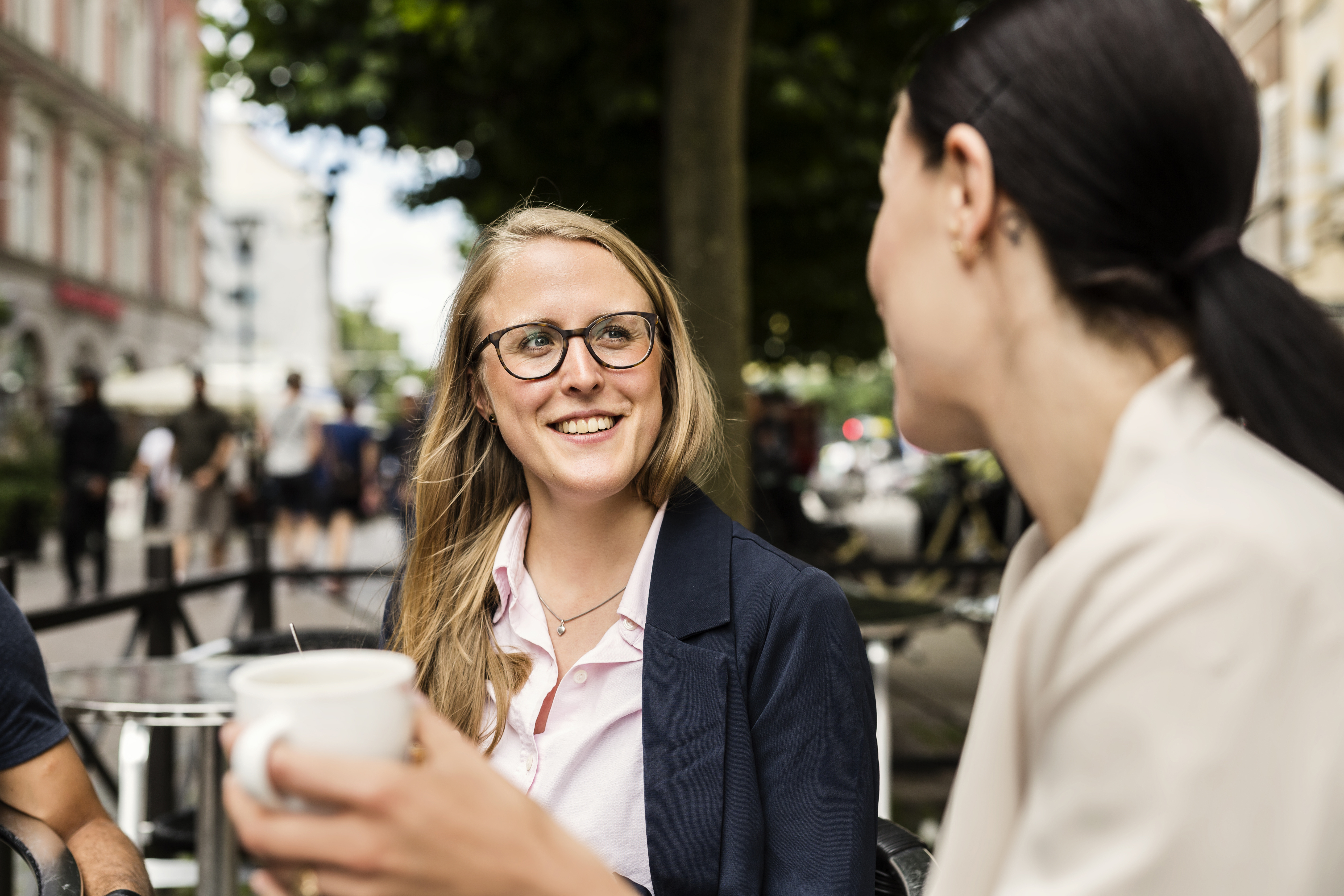 female-friends-having-coffee-in-sidewalk-cafe-2024-10-18-01-43-45-utc