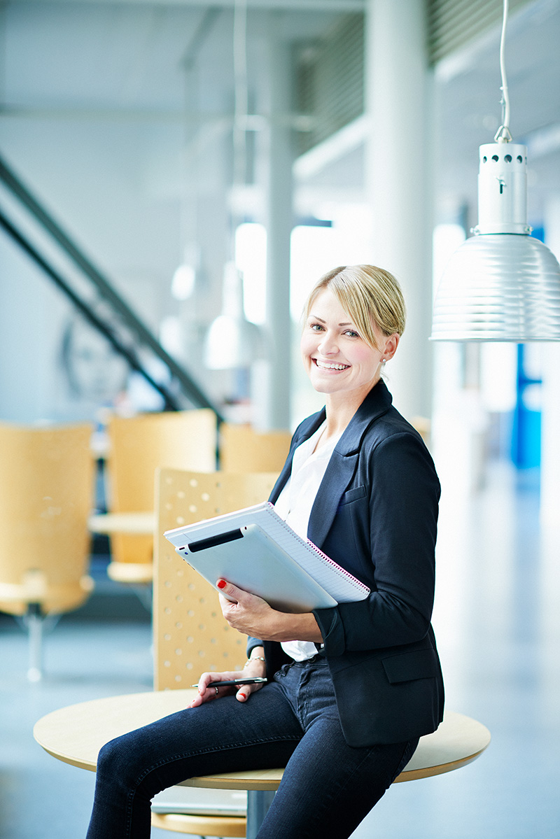 Kvinna i kostym håller i laptop och pärm, symboliserar beredskap och kontroll över information. Checklista: Lär dig hur du skyddar kommunens data mot cyberhot genom systematiska uppdateringar och säkerhetssteg.